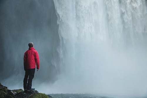 person man standing on a rock facing waterfalls human