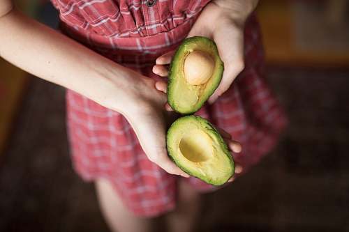 person person holding two sliced avocados human