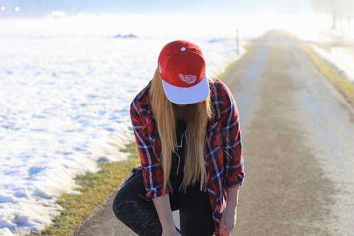 person woman bending down while touching left foot in middle of road hat