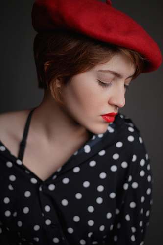 person woman wearing red newsboy hat and black and white polka-dotted button-up top human