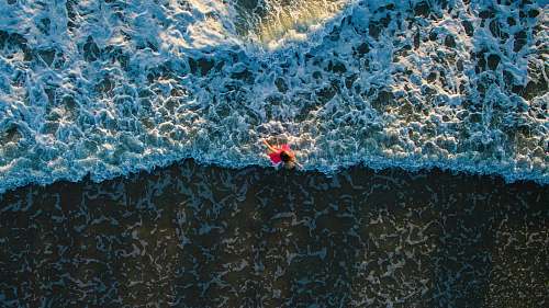water aerial photo of woman standing on shore beach