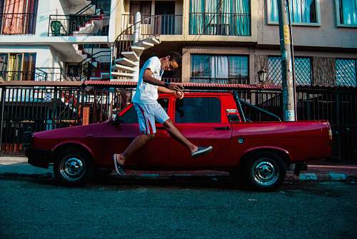 people man jumping beside red pickup truck human