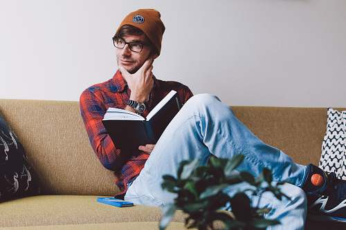 human man sitting on sofa while holding book people
