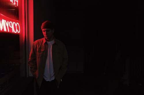 human man standing near red neon sign people