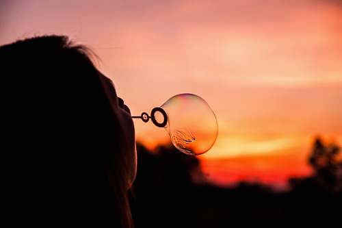 bubble shallow focus photography of person blowing bubble balloon woman