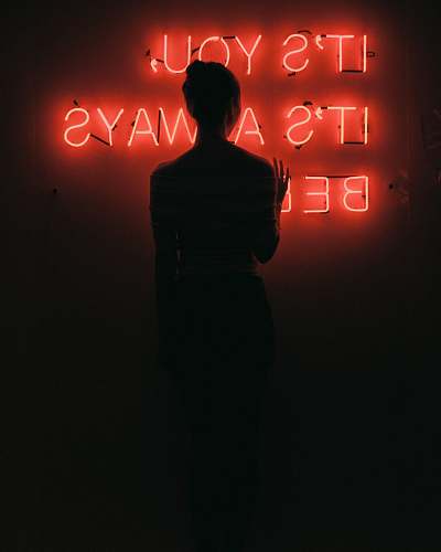 human silhouette of woman standing in front of red neon signage low light photography people