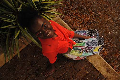 human smiling girl sitting on pavement looking up red