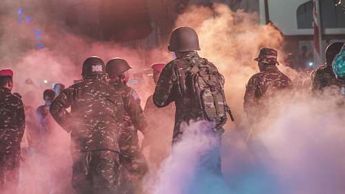 human soldiers against crowd of people with smoke trail people