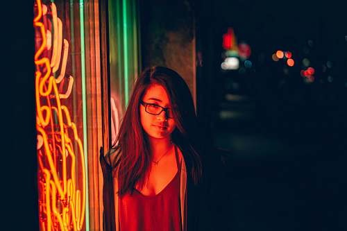human woman smirking beside glass window with turned on neon signage during night toronto