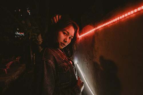 human woman wearing blue denim jacket standing beside red LED people