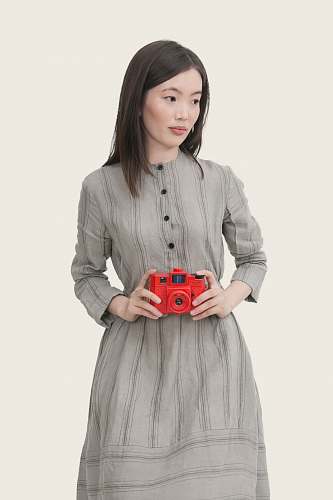 human woman wearing gray striped button-up long-sleeved dress holding red point-and-shoot camera people