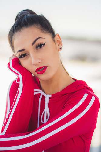 human woman wearing red and white pullover hoodie putting left hand on her face face