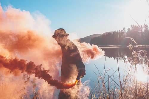 flora man holding lighted red flare grass