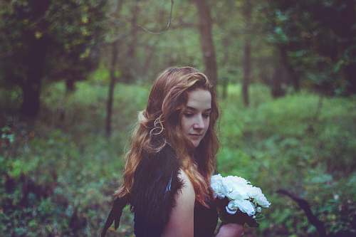 hair shallow focus photo of woman in black top holding white flowers girl