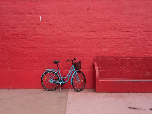 background blue step-through bicycle park beside of red bench bike