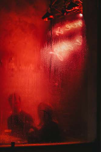 london man and woman sitting at a table behind red glass window united kingdom