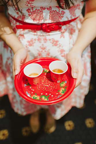 cup person holding plastic plate with two red cups coffee cup