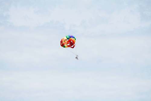 brown person on parachute sky diving under cumulus clouds pink
