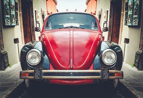 car photo of red and black Volkswagen Beetle in alley vehicle