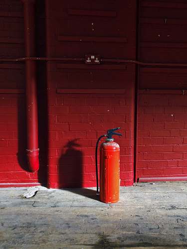 brick red fire extinguisher near red wall wall