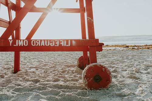 sand red lifeguard post near shoreline during daytime sun