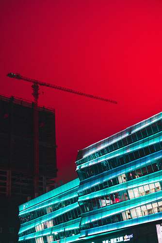 building tower crane between buildings under red sky office building
