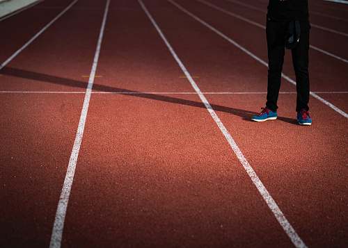 sports person standing on brown and white surface running track