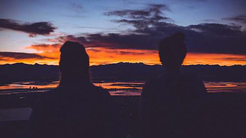 sunset silhouette photo of two women starring at sunset nature