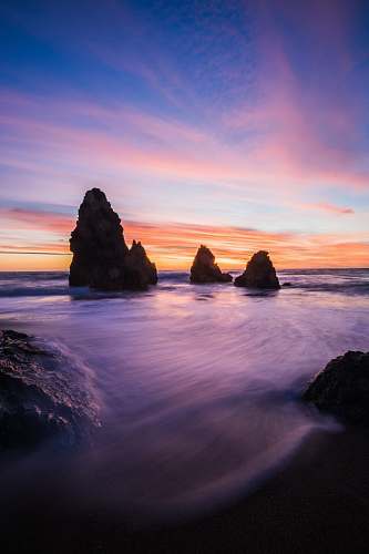 sky rock formations in body of water at blue hour sunrise