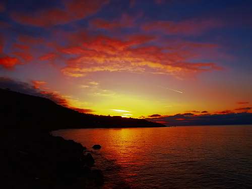 sunrise silhouette photo of island during golden hour clouds