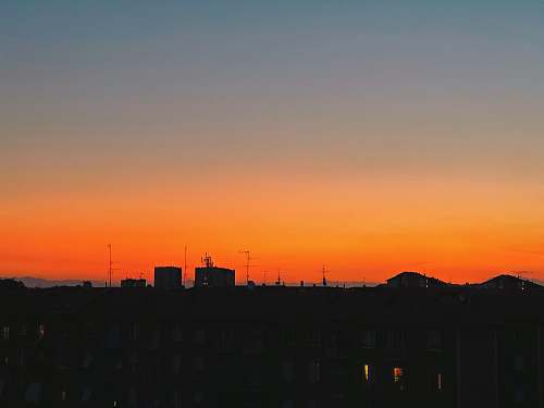 nature silhouette photography of houses during golden hour sky
