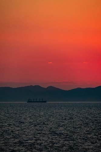 nature sillhoutte photography of ship in the sea during golden hour sky