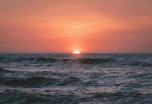 sunrise sunset on body of water sea