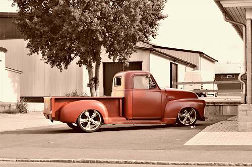 pickup sepia photography of parked classic red single cab pickup truck building