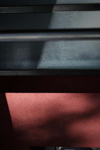 cambridge Sunlight on a black steel surface above a rough red wall abstract