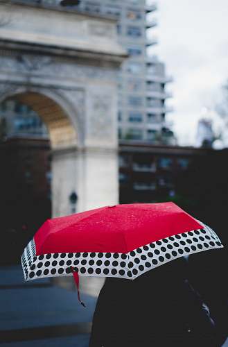 canopy person under red and white umbrella walking near building city
