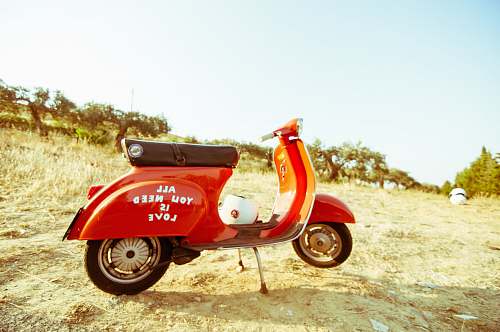 motorcycle red and black motor scooter on open field under clear blue sky motor scooter