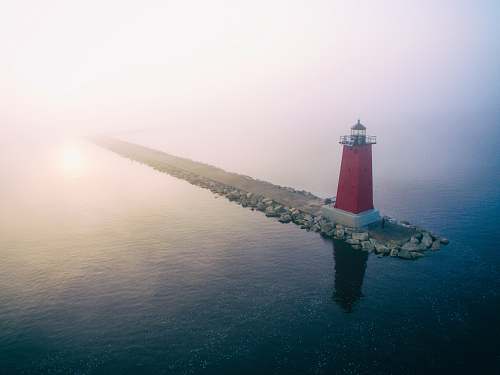 ocean red lighthouse on gray dock at daytime sea