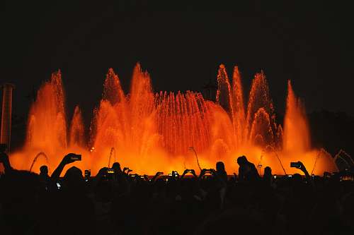 flame silhouette photography of people in front of water fountain fountain