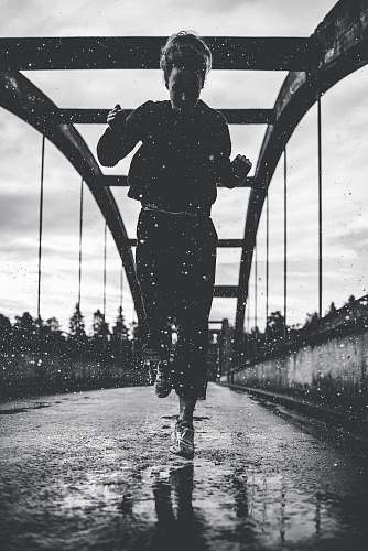 people greyscale photography of woman running on bridge person