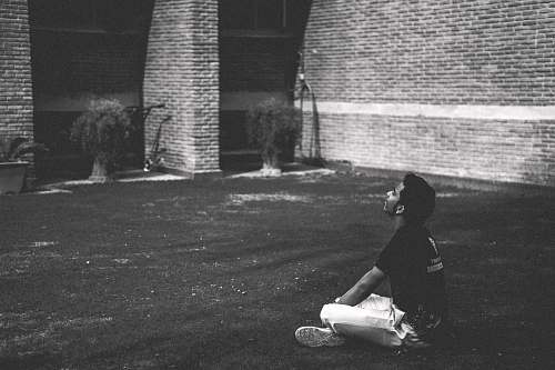 grey man in black t-shirt sitting on grass brick