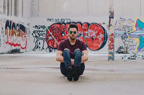 people man wearing purple shirt sitting in front of graffiti wall graffiti
