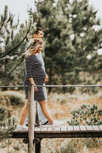 people selective focus photography of couple walking on wooden bridge person