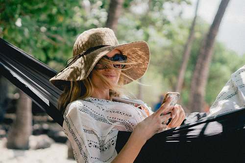 people woman lying on black hammock while holding phone person