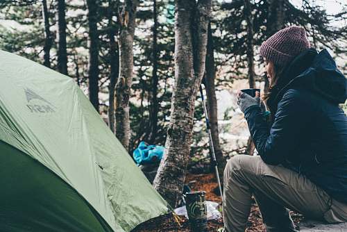 people woman sitting and holding cup of coffee camping