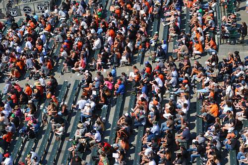 human aerial photography of people sitting on benches during daytime crowd