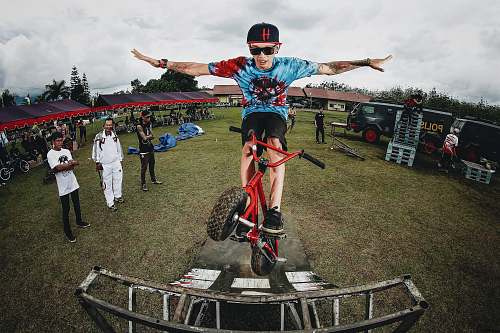 human boy doing bicycle tricks in front of many people person