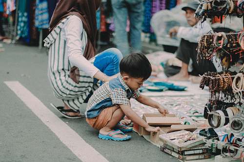 human child doing asian squat on asphalt road person