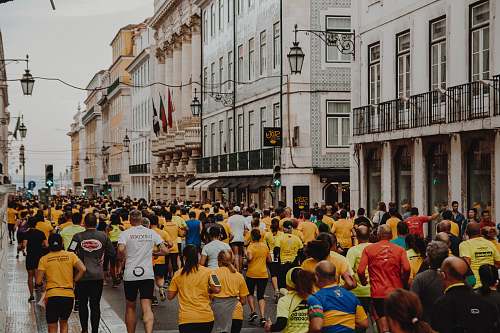 person crowd of people running on the street near buildings during daytime crowd