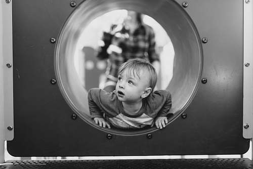 black-and-white grayscale photo of child in hole kid